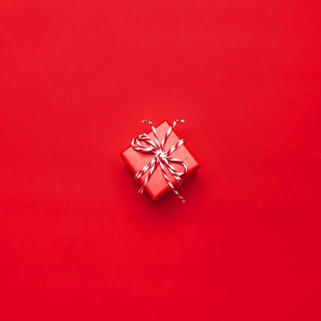 One red gift box with decorative lace on red background top view flat lay. Holiday concept new year or Christmas gift box presents Xmas holiday. Congratulations background with space for textの写真素材