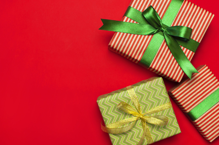 Gift boxes with green ribbon on red background top view flat lay. Holiday concept, new year or Christmas gift box, presents Xmas holiday. Congratulations background with space for text.の写真素材