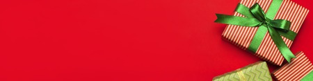 Gift boxes with green ribbon on red background top view flat lay. Holiday concept, new year or Christmas gift box, presents Xmas holiday. Congratulations background with space for text.の写真素材