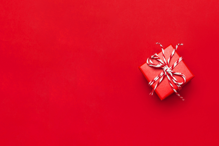 One red gift box with decorative lace on red background top view flat lay. Holiday concept new year or Christmas gift box presents Xmas holiday. Congratulations background with space for textの写真素材
