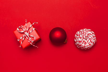 Red gift box with decorative lace, red ball, twine on red background top view flat lay. Holiday concept new year or Christmas gift box presents Xmas holiday Congratulations backgroundの写真素材