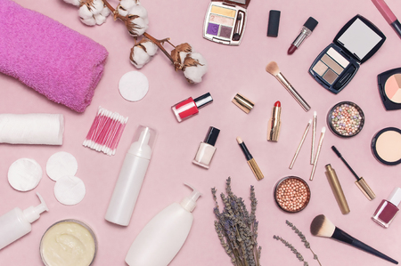 Make-up Remover Accessories. Flat lay background with cotton branch, cotton pads, ear sticks, cosmetic bottle containers, pink towel, various make-up cosmetics, mascara, powder lipstick, brushes.の写真素材