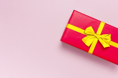 Red gift box with gold ribbon on light pink background top view flat lay. Holiday concept, birthday gift, surprise, new year or Christmas gift box. Congratulations background with space for text.の写真素材