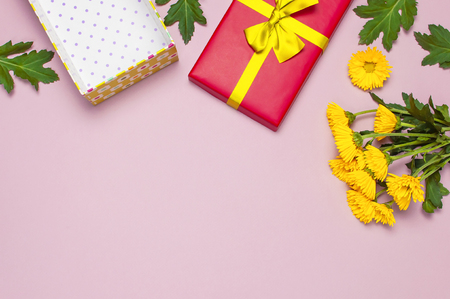 Red gift box with gold ribbon and yellow chrysanthemums on pink background top view flat lay. Holiday concept, birthday gift valentine day or anniversary. Congratulations background copy space.の写真素材