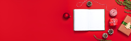 Open notebook with blank pages, gift boxes, fir branches, ball on red background flat lay top view. Christmas planning concept Holiday decorations 2019 Goals. New Year, Christmas winter decorationの写真素材