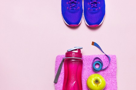 Fitness concept with Ultra violet pink female sneakers, water bottle, pink towel, apple on pastel pink background flat lay top view. Sports shoes, fitness concept of healthy lifestile.の写真素材