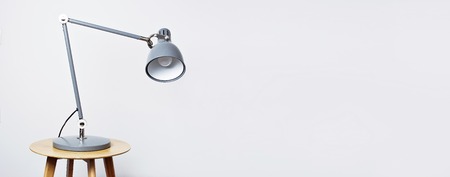 A gray table lamp in the interior against a white wall. The concept of business or education with a place for your text. Detail of interior minimalism background.の写真素材