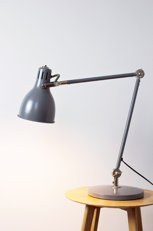 A gray table lamp in the interior against a white wall. The concept of business or education with a place for your text. Detail of interior minimalism background.の写真素材
