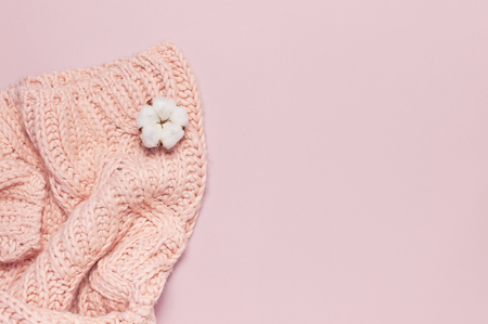 Female pink knitted sweater pullover and flower of cotton on pastel pink background top view flat lay Fashion Lady Clothes Jumper Autumn winter clothes fashion look Delicate cotton flowers Lifestyle.の写真素材