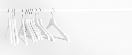 Many wooden white hangers on a rod, isolated on white wall background. Store concept, sale, design empty hanger. Place for text.の写真素材