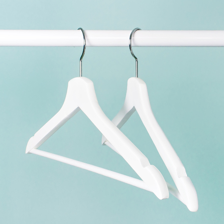 White wooden empty hangers on background of blue turquoise wall. Soft focus. Store concept, sale, design empty hanger.の写真素材