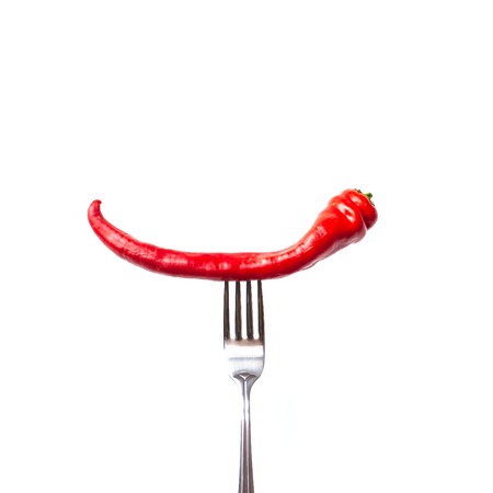 Red bitter chili pepper on the fork on white isolated background. Creative Food conceptの写真素材