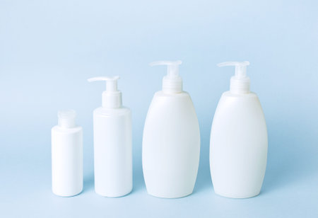 Cosmetic bottle containers on a blue minimalistic background flat lay. Blank label for branding mock-up. Natural beauty product conceptの写真素材