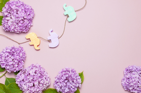 Lilac pink hydrangea flower and Multi-colored childrens wooden toys in the form of elephants on pastel pink background flat lay. Mothers Day, Birthday, Valentines Day, Womens Day celebration concept.の写真素材