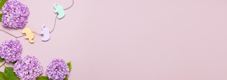 Lilac pink hydrangea flower and Multi-colored childrens wooden toys in the form of elephants on pastel pink background flat lay. Mothers Day, Birthday, Valentines Day, Womens Day celebration concept.の写真素材