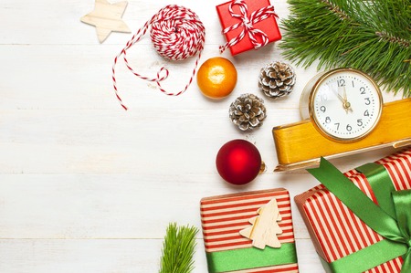 New Year or Christmas background. Retro alarm clock pine branches cones gifts presents toys red ball on white wooden background top view with copy space Christmas timer Time to celebrate Xmasの写真素材