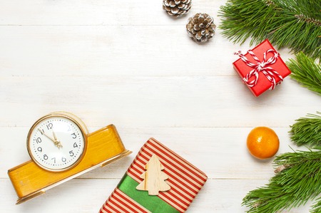 New Year or Christmas background. Retro alarm clock pine branches cones gifts presents toys red ball on white wooden background top view with copy space Christmas timer Time to celebrate Xmasの写真素材