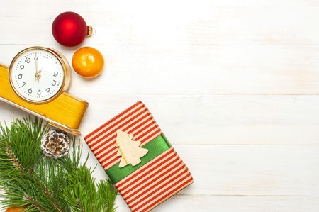 New Year or Christmas background. Retro alarm clock pine branches cones gifts presents toys red ball on white wooden background top view with copy space Christmas timer Time to celebrate Xmasの写真素材