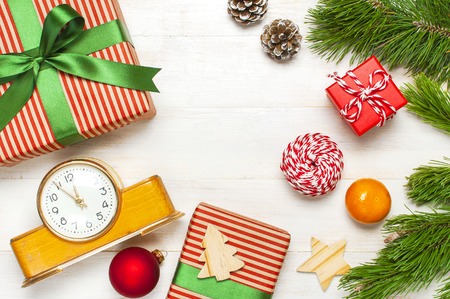 New Year or Christmas background. Retro alarm clock pine branches cones gifts presents toys red ball on white wooden background top view with copy space Christmas timer Time to celebrate Xmasの写真素材