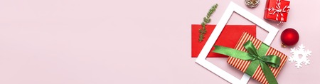 Christmas composition. White photo frame, red envelope, fir branches, cones, ball, twine, gift, wooden toys on pink background Flat lay top view. Christmas winter decoration New Year, holiday objectsの写真素材