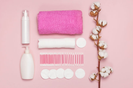 Spa concept. Flat lay background with cotton branch, cotton pads, ear sticks, cosmetic bottle containers, pink towel. Cotton Cosmetic Makeup Removers Tampons Pink background Top view copy spaceの写真素材