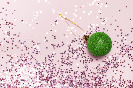Pink holographic glitter confetti form of stars, green christmas balls on pink background. Festive holiday decoration. Christmas, New Year, Xmas greeting card Flat lay top view copy spaceの写真素材