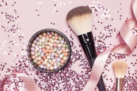 Different Cosmetic makeup brushes, blush powder balls and holographic glitter confetti in the form of stars on pink background Flat lay top view copy space Makeup accessories holiday birthday newyearの写真素材