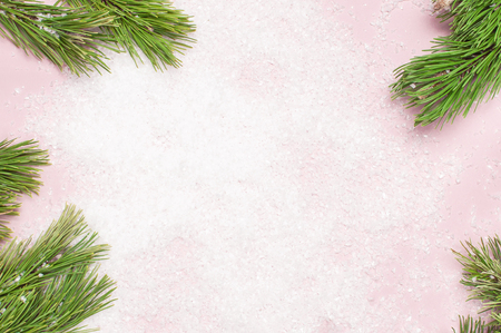 Christmas background, green pine branches on snowy pink background. Creative composition with border and copy space design top view flat lay. New Year's, holiday, christmas decorationの写真素材