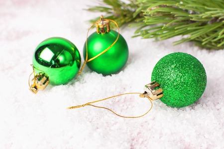Green Christmas New Year balls in the snow and pine branches on pink background Flat Lay copy space. Holiday Baubles, beautiful Decoration Festive decor celebration Xmas holiday greeting cardの写真素材