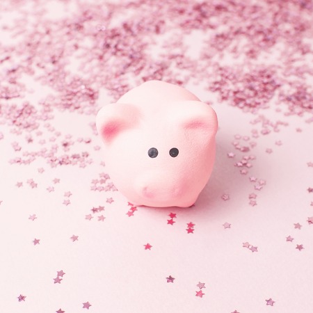 Ceramic toy pink pig symbol of the new year and holographic glitter confetti form of stars on pink background Flat Lay copy space. Decoration Festive decor celebration Xmas holidayの写真素材