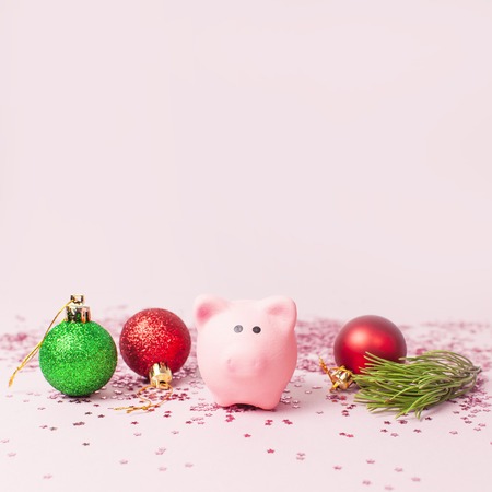 Ceramic toy pink pig symbol of the new year Green Red Christmas balls and holographic glitter confetti form of stars on pink background Flat Lay copy space. Decoration Festive decor celebrationの写真素材
