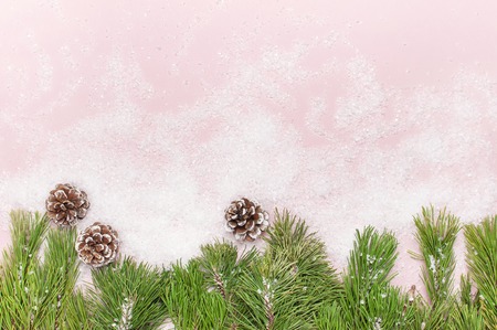Christmas background, green pine branches, cones decorated with snow on snowy pink background. Creative composition with border and copy space design top view New Year's, holiday, decorationの写真素材