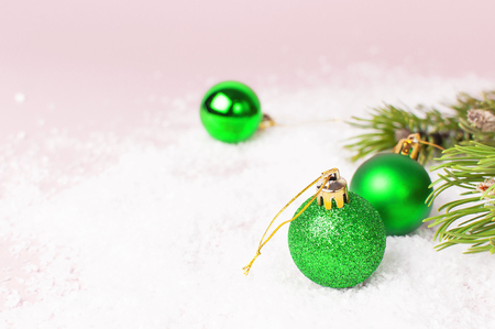 Green Christmas New Year balls in the snow and pine branches on pink background Flat Lay copy space. Holiday Baubles, beautiful Decoration Festive decor celebration Xmas holiday greeting cardの写真素材