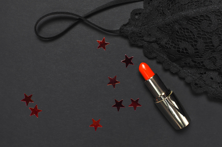 Black lace bra underwear, red lipstick, holographic confetti on dark background top view flat lay. Female essential erotic accessories, fashionable underwear gift for birthday new year christmasの写真素材