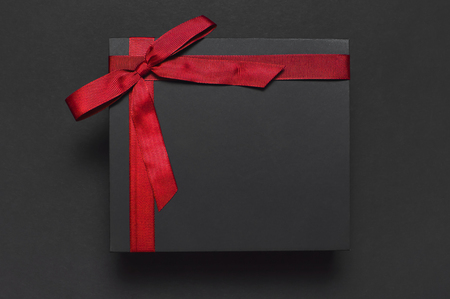Black gift box with red ribbon on dark background top view flat lay. Holiday concept, birthday gift, father's day, Valentine's Day, new year or Christmas presents Xmas Congratulations backgroundの写真素材