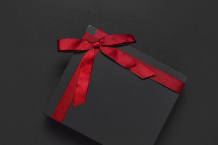 Black gift box with red ribbon on dark background top view flat lay. Holiday concept, birthday gift, father's day, Valentine's Day, new year or Christmas presents Xmas Congratulations backgroundの写真素材