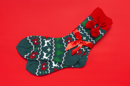Woolen socks with a Christmas New Year ornament on red background top view flat lay. Holiday concept, Festive socks, presents Xmas. Congratulations background with space for text Clothes for the coldの写真素材