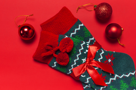 Woolen socks with a Christmas New Year ornament, balls, glitter confetti on red background top view flat lay. Holiday concept, presents Xmas. Congratulations background with space for textの写真素材