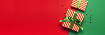 Gift boxes with green ribbon and holographic glitter confetti form of stars on red green background top view flat lay space for text. Holiday concept, new year or Christmas gift box, presents Xmasの写真素材