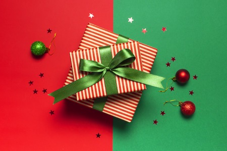 Gift boxes with green ribbon and holographic glitter confetti form of stars on red green background top view flat lay space for text. Holiday concept, new year or Christmas gift box, presents Xmasの写真素材