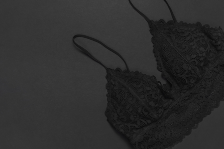 Black lace bra underwear on dark background top view flat lay with copy space. Female essential erotic clothes, fashionable beautiful underwear. Concept of sale in the store, shoppingの写真素材