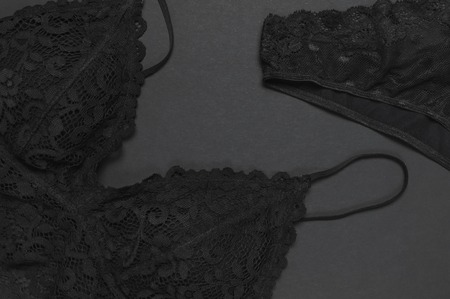 Black lace set of women's underwear on dark background. Top view flat lay with copy space. Bra and panties, fashionable erotic female clothing, beautiful underwear. Advertising, shopping conceptの写真素材