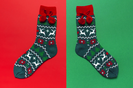 Woolen socks with a Christmas New Year ornament on red green background top view flat lay. Holiday concept, Festive socks, presents Xmas. Congratulations background with space for textの写真素材