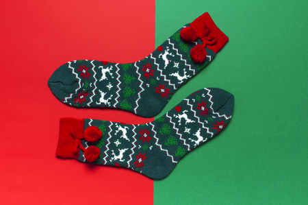 Woolen socks with a Christmas New Year ornament on red green background top view flat lay. Holiday concept, Festive socks, presents Xmas. Congratulations background with space for textの写真素材