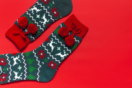 Woolen socks with a Christmas New Year ornament on red background top view flat lay. Holiday concept, Festive socks, presents Xmas. Congratulations background with space for text Clothes for the coldの写真素材