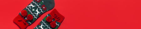 Woolen socks with a Christmas New Year ornament on red background top view flat lay. Holiday concept, Festive socks, presents Xmas. Congratulations background with space for text Clothes for the coldの写真素材