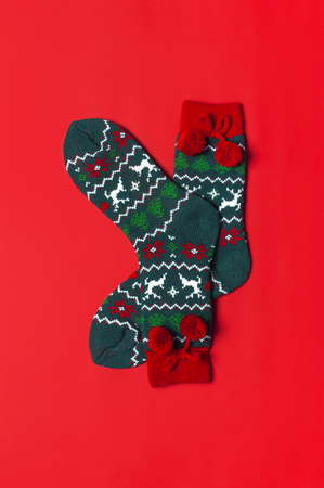 Woolen socks with a Christmas New Year ornament on red background top view flat lay. Holiday concept, Festive socks, presents Xmas. Congratulations background with space for text Clothes for the coldの写真素材