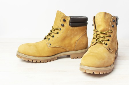 Yellow men's work boots from natural nubuck leather on wooden white background. Trendy casual shoes, youth style. Concept of advertising autumn winter shoes, sale, shopの写真素材