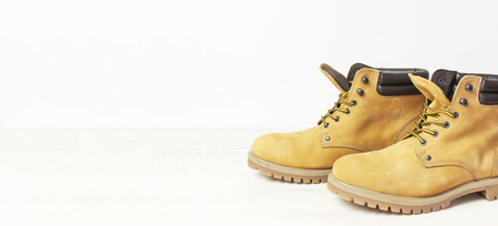 Yellow men's work boots from natural nubuck leather on wooden white background. Trendy casual shoes, youth style. Concept of advertising autumn winter shoes, sale, shopの写真素材