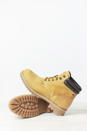 Yellow men's work boots from natural nubuck leather on wooden white background. Trendy casual shoes, youth style. Concept of advertising autumn winter shoes, sale, shopの写真素材